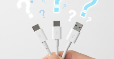 Main tenant plusieurs câbles USB avec points d'interrogation symbolisant la confusion