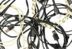 Enchevêtrement de vieux câbles de chargement USB-C, Micro-USB et Lightning, certains noirs et d'autres tressés en nylon jaune, illustrant le stock de câbles inutilisés à recycler ou à détourner.