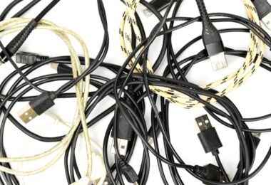 Enchevêtrement de vieux câbles de chargement USB-C, Micro-USB et Lightning, certains noirs et d'autres tressés en nylon jaune, illustrant le stock de câbles inutilisés à recycler ou à détourner.