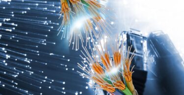 Vue rapprochée de fibres optiques multicolores sectionnées montrant le cœur en verre et les gaines de protection sur un fond numérique bleu.
