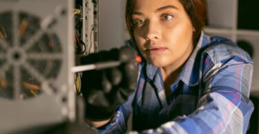 Technicienne examinant les composants internes d'une unité centrale ouverte pour une opération de maintenance ou de recyclage matériel.