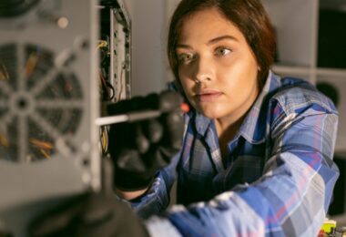 Technicienne examinant les composants internes d'une unité centrale ouverte pour une opération de maintenance ou de recyclage matériel.